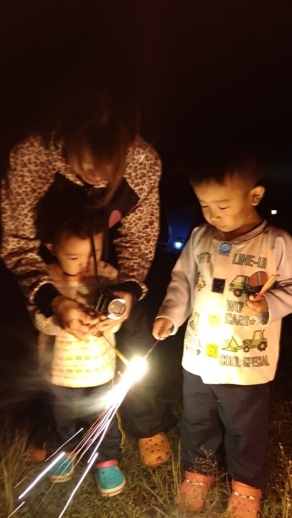 夜のキャンプ場で花火をする子供たち