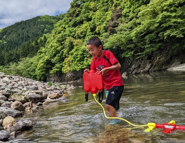 川で水鉄砲で遊ぶ子供